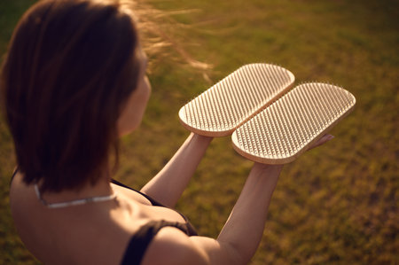 Caucasian woman holds sadhu nail board outdoors. Concentrated female practicing yoga alone on the grassの写真素材
