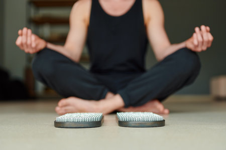 Selective focus. Practice of standing on nails. Man meditation after practice of standing on sadhu board in yoga studio. Concept on healthy lifestyle.の写真素材