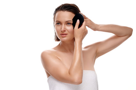Gua Sha facial skin massage. European woman in white bath towel massages her face. Isolate white backgroundの写真素材