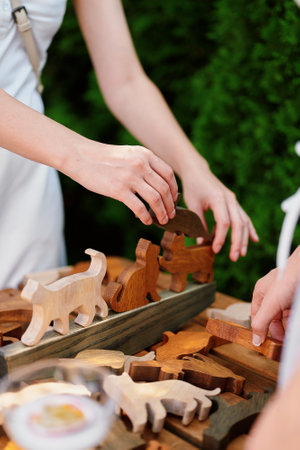 Several wooden animal figurines, primarily cats, being arranged by hands. The figurines are made of different types of wood, giving them various shades of brown. Set on a wooden surface or standの写真素材