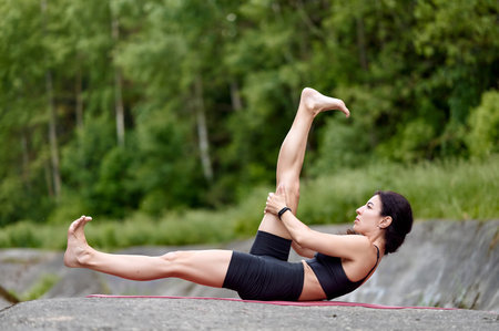 Yoga instructor performing side angle pose outdoors, one arm extended upwards, deep breathing...