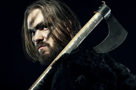 Photo of dangerous viking warrior with axe prepare to battle on black background.