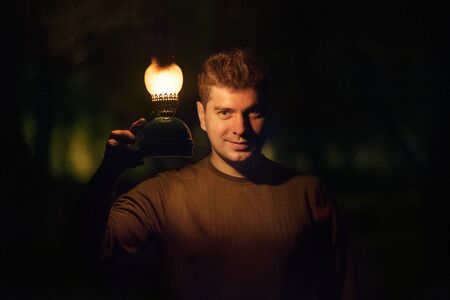Young man with a burning lamp ooking into camera.の写真素材