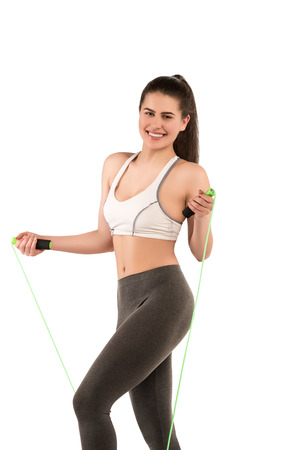 Happy sporty fitness woman on white background with jump ropeの写真素材