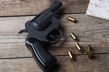 Weapons revolver with bullets and a map on a wooden surfaceの写真素材