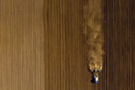 Harvester working in the field at spring and plowing the fieldの写真素材