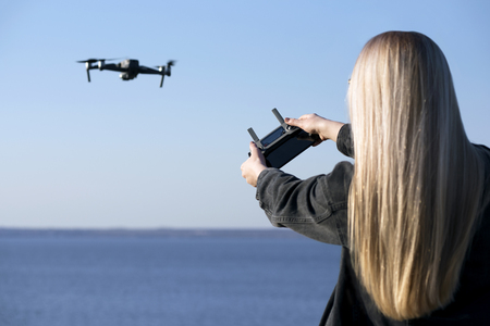 The girl controls the drone on a background of blue skyの写真素材