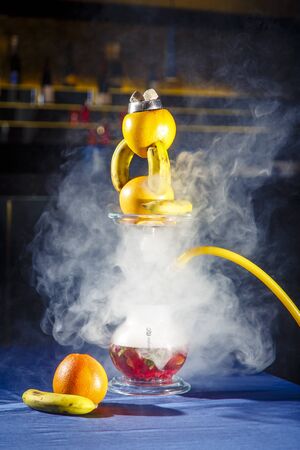 Hookah with a round transparent flask in which there is a red liquid. Hookah bowl of oranges and...