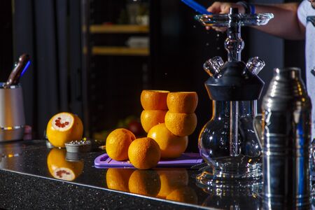 Preparation of hookah. On the bar there is an empty hookah and oranges intended for hookah.
