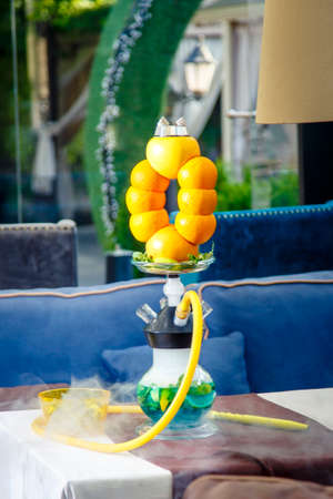 Hookah on oranges and bananas. Citrus hookah. Hookah with round clear bulb with a red liquor. A bowl...