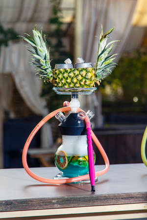 Hookah on pineapple. Pineapple hookah. Hookah with round clear bulb in which the red liqueur float aplysina and chopped mint leaves. The bowl of the hookah pineapple. Lots of smoke.の写真素材