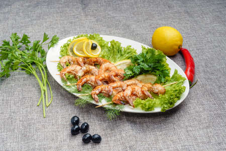 King prawns on a lettuce leaf on a white plate. Decorated with lemon, olives and parsleyの写真素材