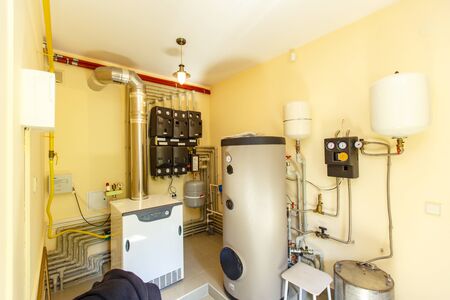 Boiler room and heating system in the cottage. Gas and electric boilers, voltage stabilization system. Hot water is distributed through the house heating systemの写真素材