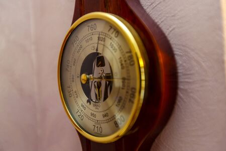 A vintage barometer Clock hangs on a pink wall. shot on a large aperture, blurry background. Golden rim, wooden base, beautiful arrowsの写真素材