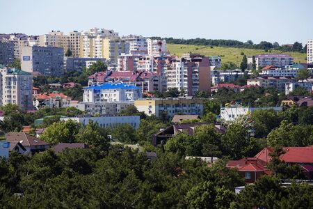 Urban landscape. Numerous multi-storey houses stand on the slope. Rhythm, Windows, roofs. Greenery,...