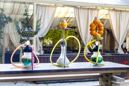 Three hookahs stand on the table in the cafe. Hookah on a pineapple hookah on the orange, Shisha on...