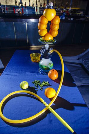 Hookah on oranges. Citrus hookah. Hookah with round clear bulb with a red liquor. A bowl of hookah...