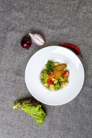 Salad with black sea RAPAN meat, dressed with honey sauce. With rye crackers. On a gray canvas cloth, next to the salad, onion headの写真素材