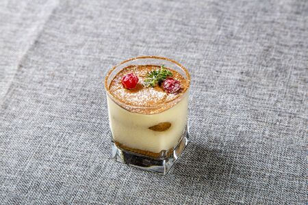 Panna cotta dessert in a transparent glass, decorated with cherries and mint on top. a glass on a gray canvas.の写真素材