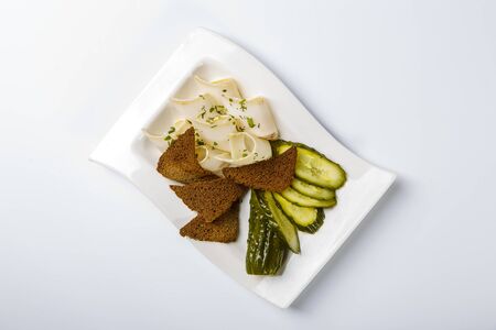 Snack to vodka. Plate with lard slices, rye bread, slices of pickle. The view from the top. On white...