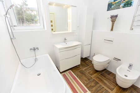 White bathroom in a minimalist style. Bright white tiles, bathroom, toilet, sink, beige tiles on the...
