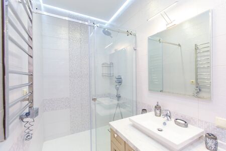 bathroom with elegant rectangular washbasin, toilet and shower. Mirror with light on top. The white...