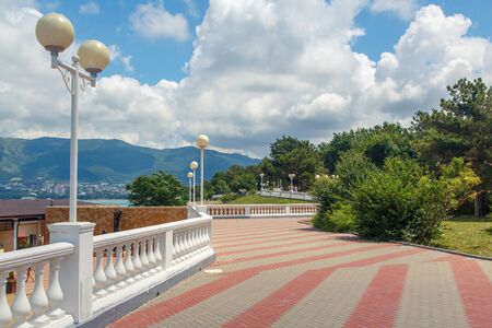 The embankment of the resort of Gelendzhik in clear Sunny weather. White balustrade and street lights. In the background, Gelendzhik Bay and the Caucasus mountainsの写真素材