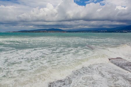 Storm in Gelendzhik Bay. Beach of Gelendzhik resort. Storm waves roll down a low stone pier located...