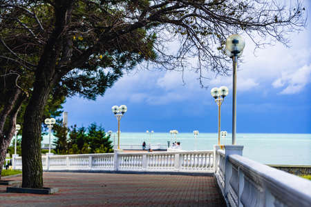 The embankment of the resort town in autumn. The embankment with a balustrade and numerous lanterns. A green sea and a dark, stormy sky. People walk along the embankment and look into the sea. Gelendzhik resort, Black Seaの写真素材