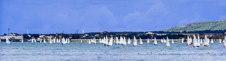 Youth yacht regatta in Gelendzhik Bay. Autumn dark sky, green stormy sea. Mountains and houses in the background. Gelendzhik. The black seaのeditorial素材