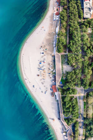 On the pebble beach, near the seashore, there are yacht hulls and trolleys for transporting yachts. Near the embankment with a balustrade. Preparation for the sailing regatta. Top view.の写真素材