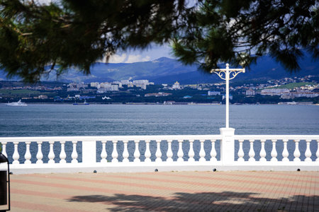 A look through the balustrade of the seaside resort at the sea, mountains and yachts in the sea. Summer, white clouds, vacation, tourismの写真素材