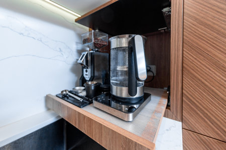 A kitchen sink with a coffee maker on top of it. The sink is black and the coffee maker is silverの写真素材