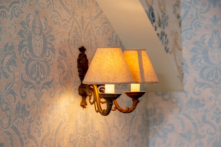 A wall with a blue and white pattern and two lamps hanging from the wall. The lamps are lit up and the wall is illuminatedの写真素材