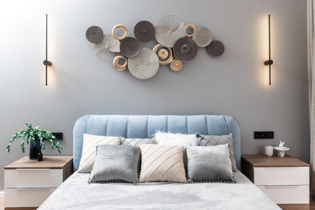 A bed with pillows and a lamp on the nightstand. The bed is blue and the pillows are white and grayの写真素材