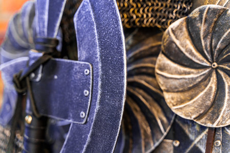 A sword is displayed next to a shield with a swirl design. The sword is old and has a black handleの写真素材