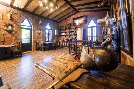 A room with a knight's helmet on a table. The room is decorated with antlers and has a rustic feelの写真素材