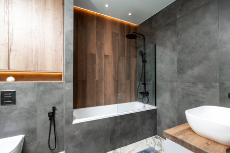 A bathroom with a toilet, bathtub, and sink. The bathroom has a modern design with a wooden...