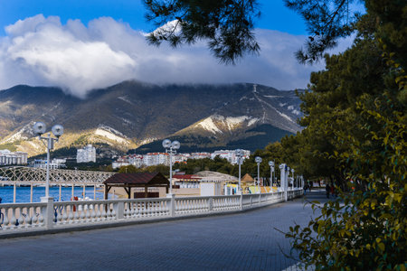 Gelendzhik resort in winter. Nord-Ost wind begins. Signs of storm - clouds over Caucasus Mountains. Off-season. Deserted beach, strong wind. Embankment and balustrade in foregroundの写真素材
