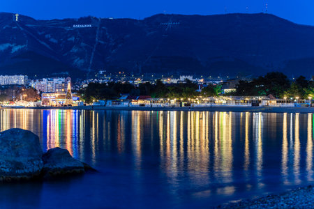 Gelendzhik, Krasnodar Territory, Russia. Gelendzhik resort embankment in the evening, the lamps are rhythmically reflected in Gelendzhik Bay. A beautiful night view of a city with a large body of water in the background.の写真素材