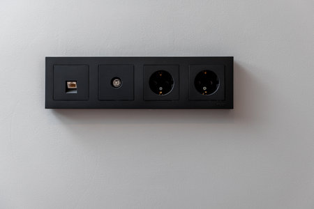 A black electrical box with four outlets. The box is on a white wall