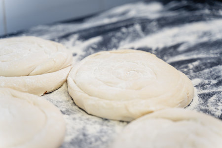 A close up of dough with a lot of flour on it. The dough is in the middle of the image and is...