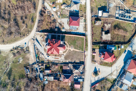A red house is in the middle of a residential area. The houses are all red and there are a few cars parked on the streetの写真素材