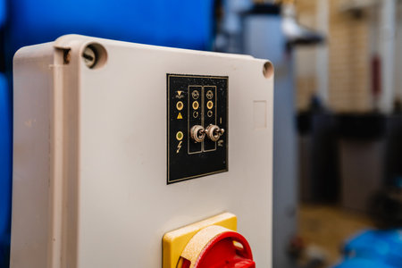 A switch is on a wall. The switch is red and yellow