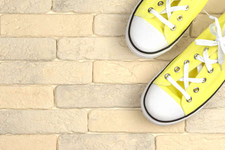 yellow sneakers on a brick wall