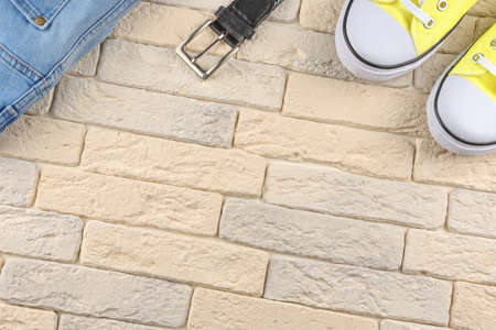 Jeans and sport shoes on a light background of bricks, top view