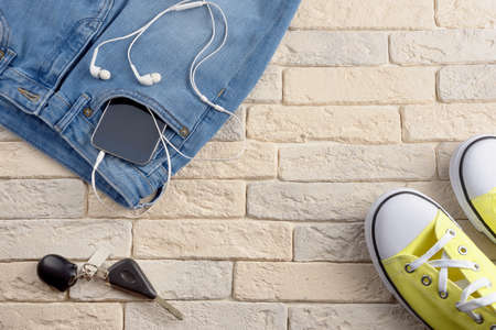 Jeans and sport shoes on a light background of bricks, top viewの写真素材