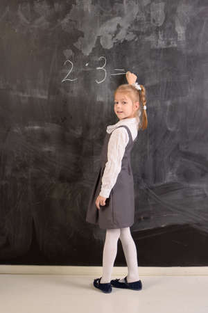 Student writes with chalk on a blackboard