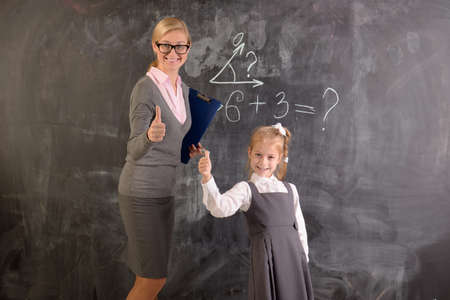 Young teacher and student stand at the blackboardの写真素材