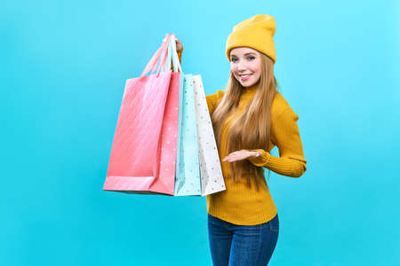 Fashionista girl with bags. Young happy woman with purchases. Joyful beauty was on sale, on a blue...
